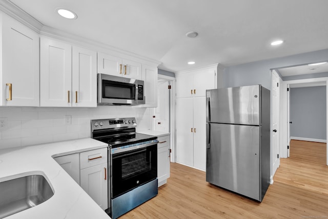 kitchen featuring light wood finished floors, backsplash, light stone counters, stainless steel appliances, and white cabinetry