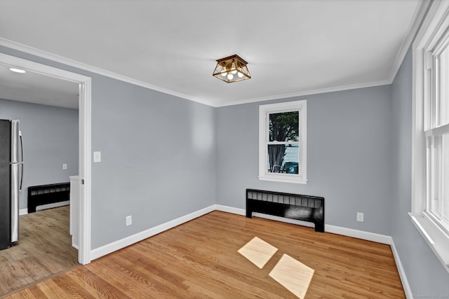 unfurnished room featuring a notable chandelier, crown molding, baseboards, and wood finished floors