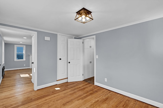 unfurnished bedroom featuring light wood finished floors, crown molding, and baseboards