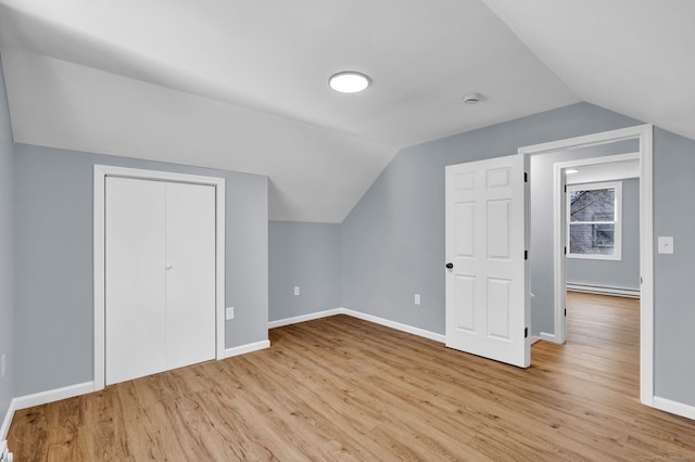 additional living space featuring baseboards, baseboard heating, lofted ceiling, and wood finished floors