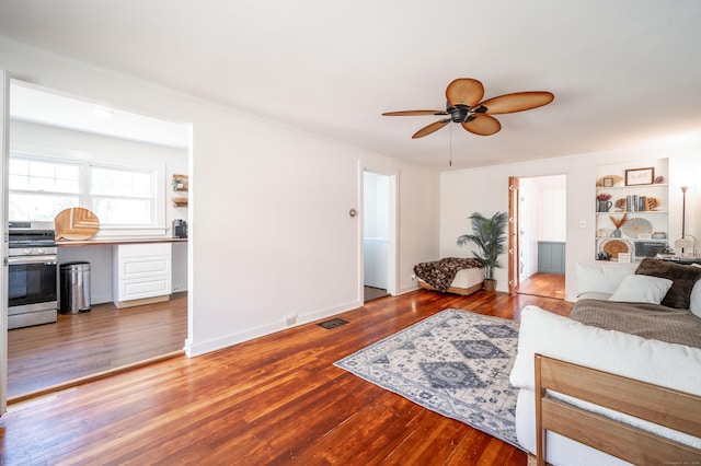 living room with visible vents, baseboards, wood-type flooring, and ceiling fan