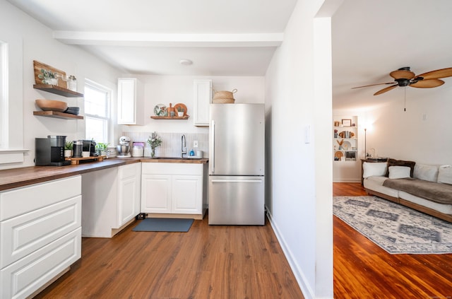 kitchen with open shelves, white cabinetry, a sink, and freestanding refrigerator