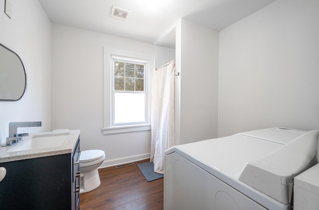 bathroom with visible vents, washing machine and dryer, toilet, and wood finished floors