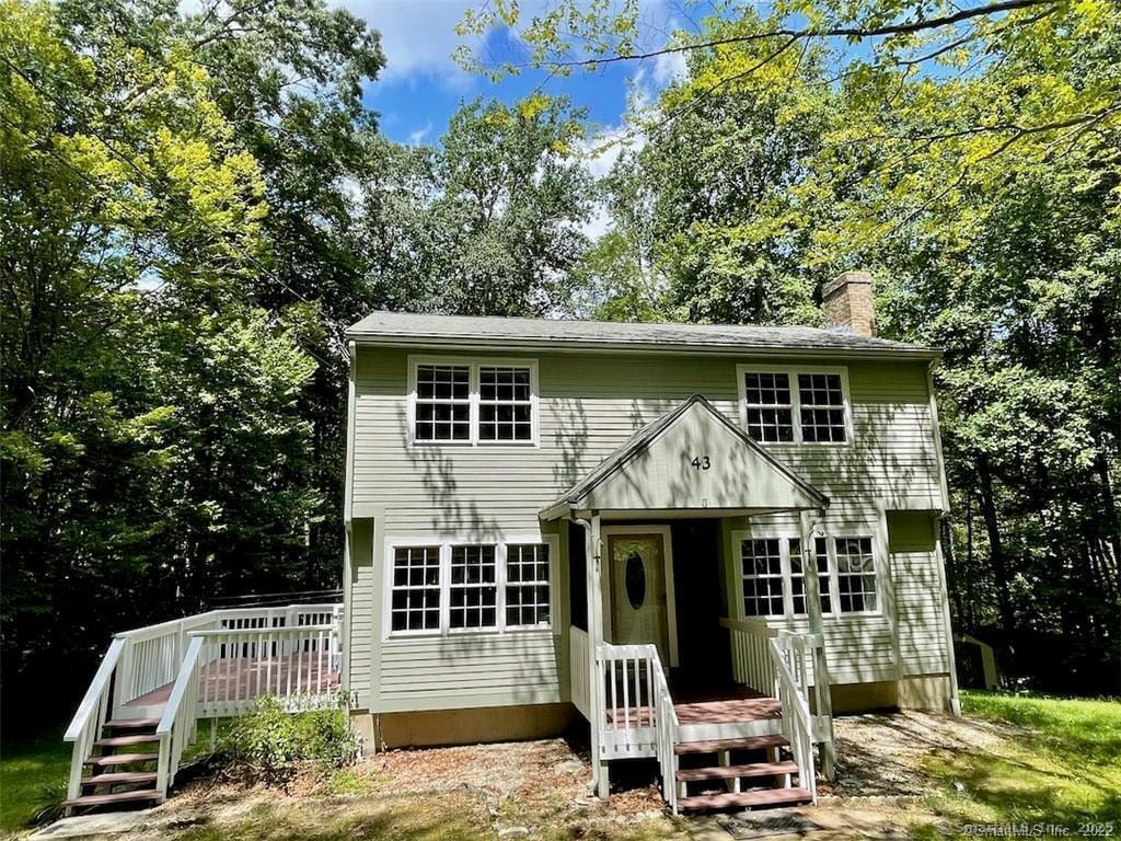 colonial inspired home with a wooden deck and a chimney