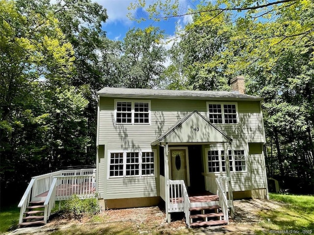 colonial inspired home with a wooden deck and a chimney