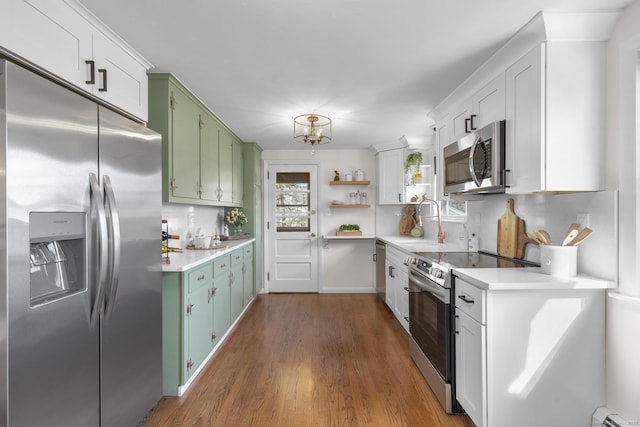 kitchen with open shelves, a sink, light countertops, appliances with stainless steel finishes, and green cabinets