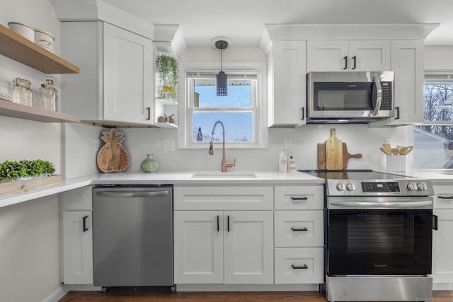 kitchen with a sink, open shelves, appliances with stainless steel finishes, and light countertops