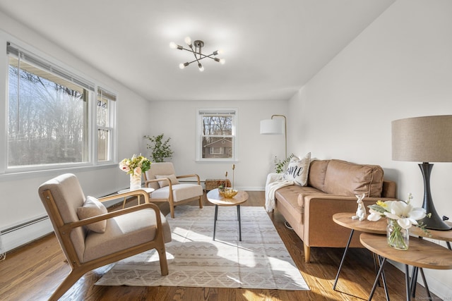 living room featuring a chandelier, baseboards, baseboard heating, and wood finished floors