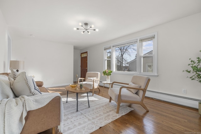 living area with a notable chandelier, wood finished floors, baseboards, and a baseboard radiator