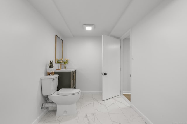 bathroom with baseboards, toilet, and marble finish floor