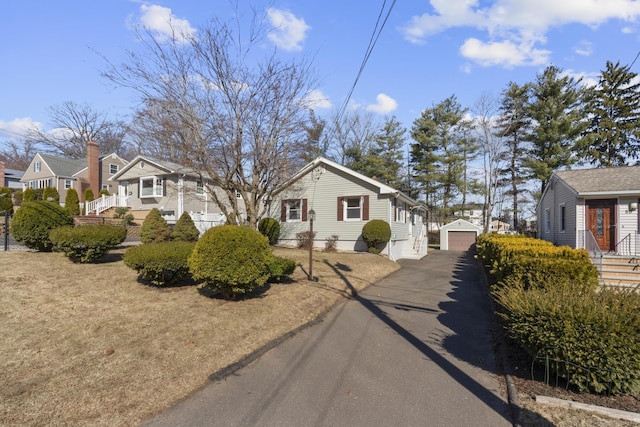 view of side of property featuring a residential view, driveway, a detached garage, and an outdoor structure