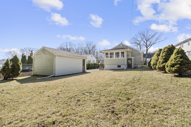 rear view of property with an outdoor structure, a lawn, and fence