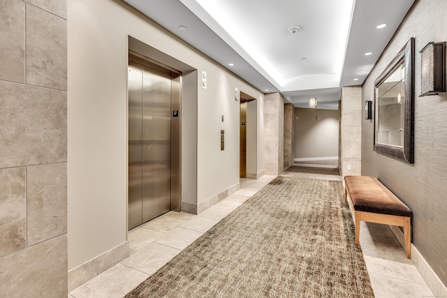 hall with recessed lighting, a tray ceiling, elevator, and light tile patterned flooring