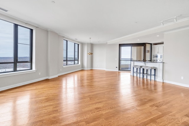 unfurnished living room with plenty of natural light, baseboards, light wood-type flooring, and visible vents