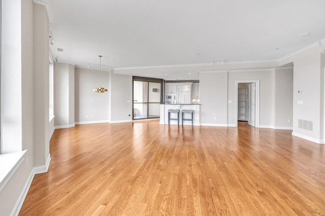 unfurnished living room with light wood finished floors, visible vents, crown molding, baseboards, and an inviting chandelier