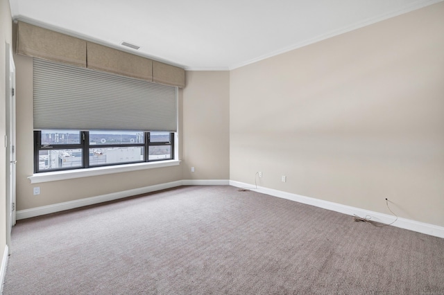 carpeted empty room with baseboards, visible vents, and ornamental molding