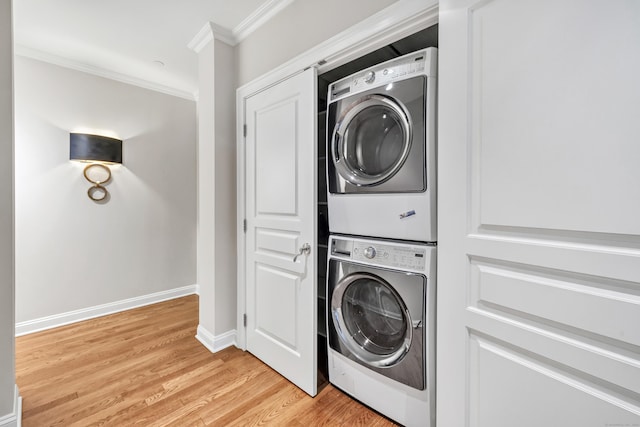 laundry room with crown molding, baseboards, light wood-type flooring, stacked washer and dryer, and laundry area