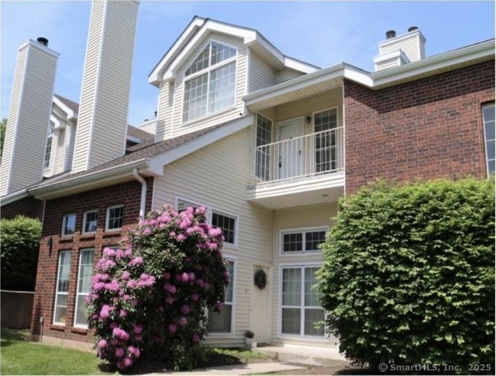 exterior space with a balcony and brick siding