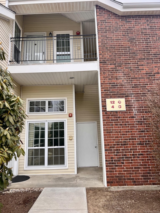 property entrance with a balcony and brick siding