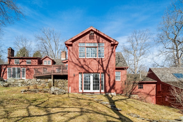 rear view of property featuring a wooden deck, french doors, a chimney, and a yard