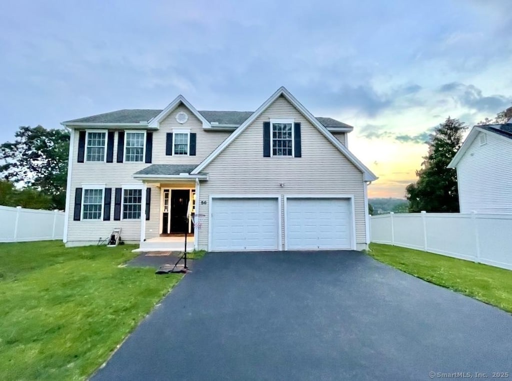 view of front of house with aphalt driveway, an attached garage, a front yard, and fence