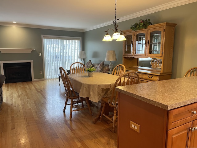 dining room with crown molding, a fireplace, and light wood-type flooring