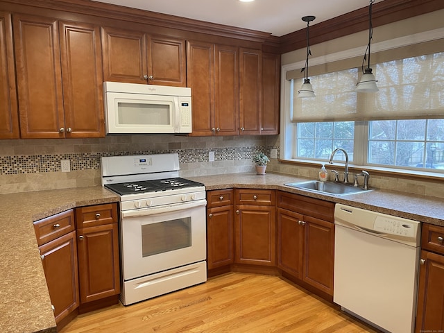 kitchen with a sink, decorative backsplash, white appliances, and light wood-style floors