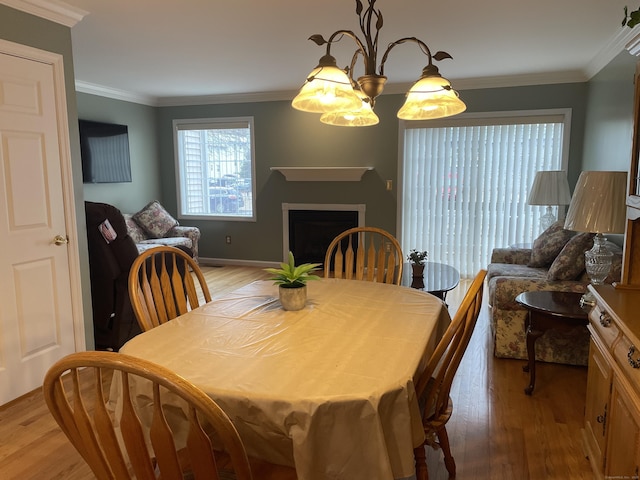 dining space featuring light wood-type flooring, ornamental molding, and a fireplace