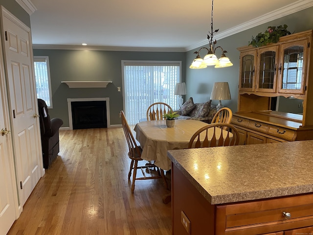 dining space with baseboards, light wood-style floors, ornamental molding, and a fireplace