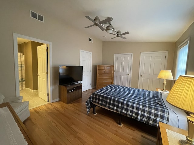 bedroom with visible vents, baseboards, lofted ceiling, and wood finished floors