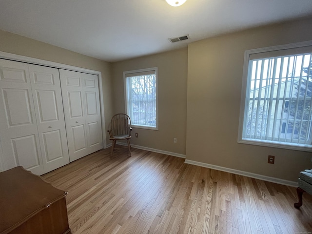 unfurnished bedroom with a closet, visible vents, light wood-type flooring, and baseboards