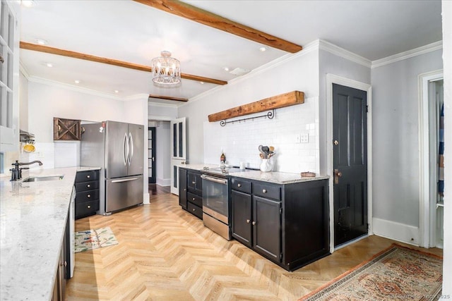 kitchen featuring a notable chandelier, ornamental molding, a sink, dark cabinetry, and appliances with stainless steel finishes