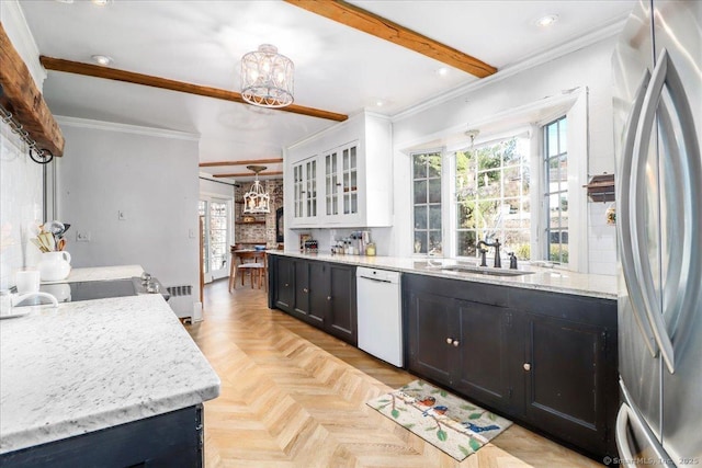 kitchen with a sink, radiator heating unit, freestanding refrigerator, white dishwasher, and a chandelier