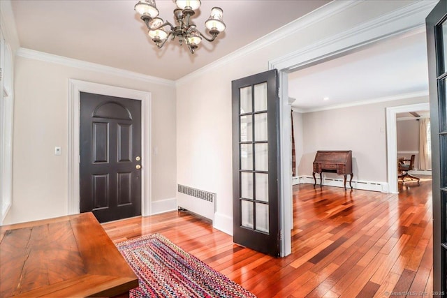 foyer entrance featuring a baseboard radiator, radiator heating unit, hardwood / wood-style flooring, crown molding, and a chandelier