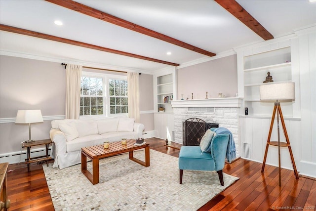 living room featuring built in shelves, beam ceiling, wood-type flooring, a stone fireplace, and a baseboard radiator