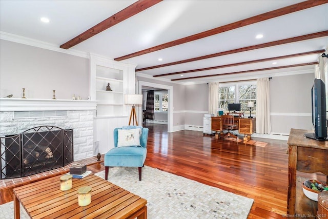 living room with beamed ceiling, a baseboard heating unit, wood finished floors, crown molding, and baseboards