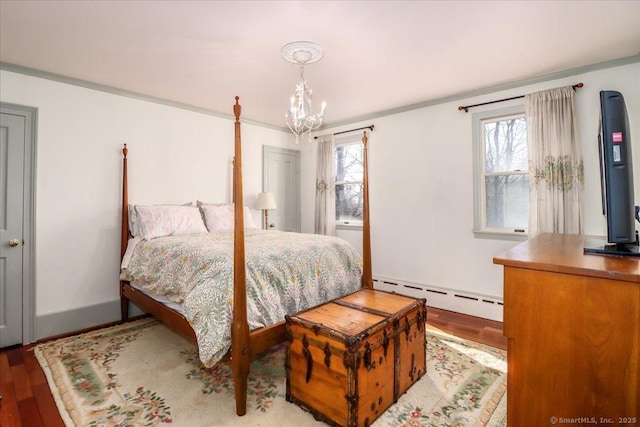 bedroom featuring a baseboard heating unit, wood finished floors, crown molding, baseboards, and a chandelier