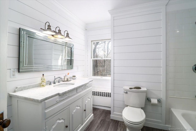 bathroom with toilet, wood finished floors, radiator heating unit, crown molding, and vanity