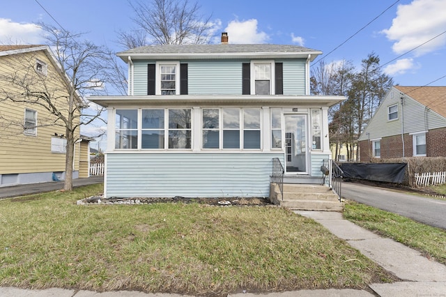 american foursquare style home featuring a chimney, a front yard, and a sunroom