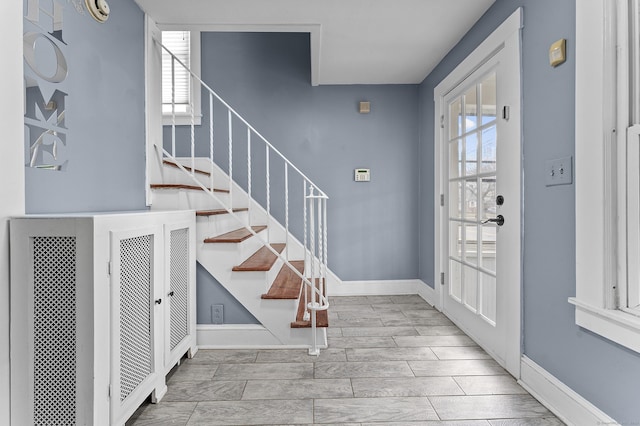 entrance foyer featuring a wealth of natural light, stairway, and baseboards