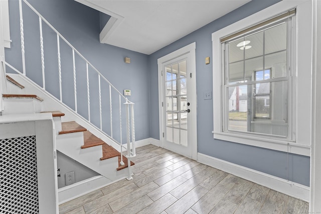 foyer entrance with baseboards, wood finished floors, and stairs