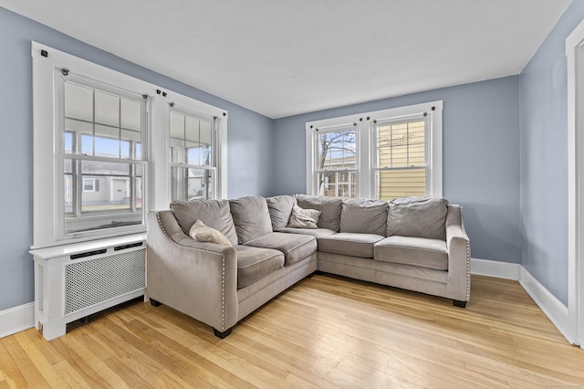 living room with light wood-style flooring, radiator heating unit, and baseboards