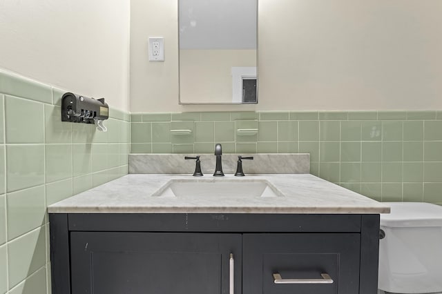 half bathroom featuring toilet, vanity, and tile walls