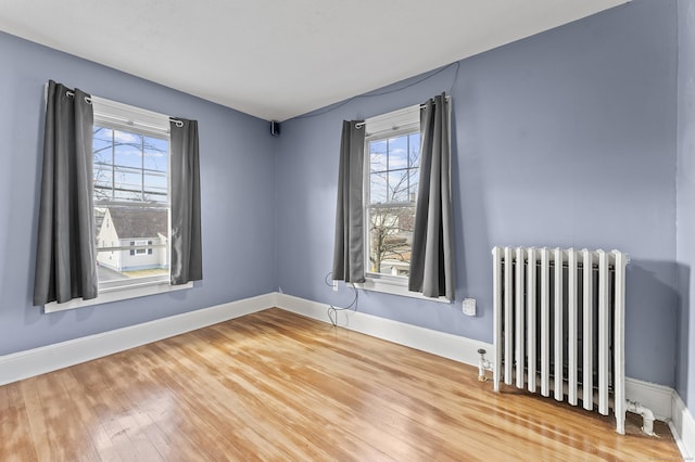 empty room with hardwood / wood-style flooring, radiator heating unit, and baseboards