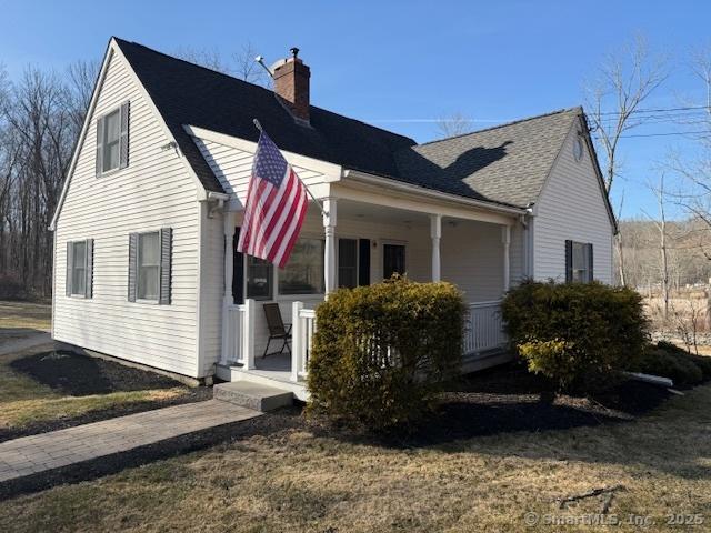 view of side of home with covered porch, a chimney, and roof with shingles