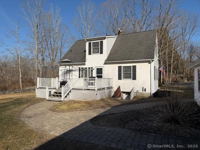 back of house with roof with shingles and a deck