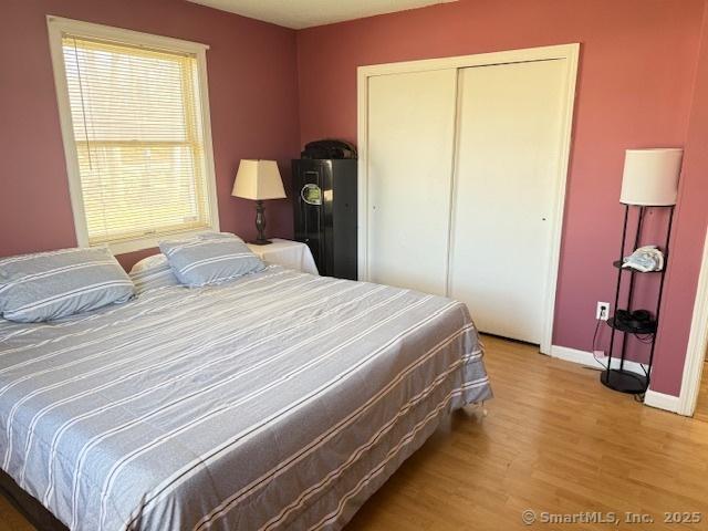 bedroom with light wood-style floors, a closet, and baseboards