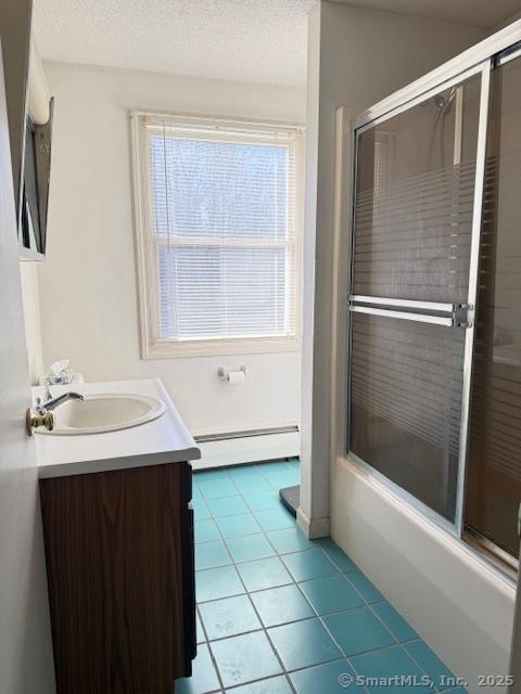 bathroom with tile patterned floors, baseboard heating, vanity, and a textured ceiling