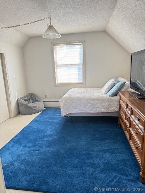 bedroom with a textured ceiling, a baseboard heating unit, lofted ceiling, and dark colored carpet