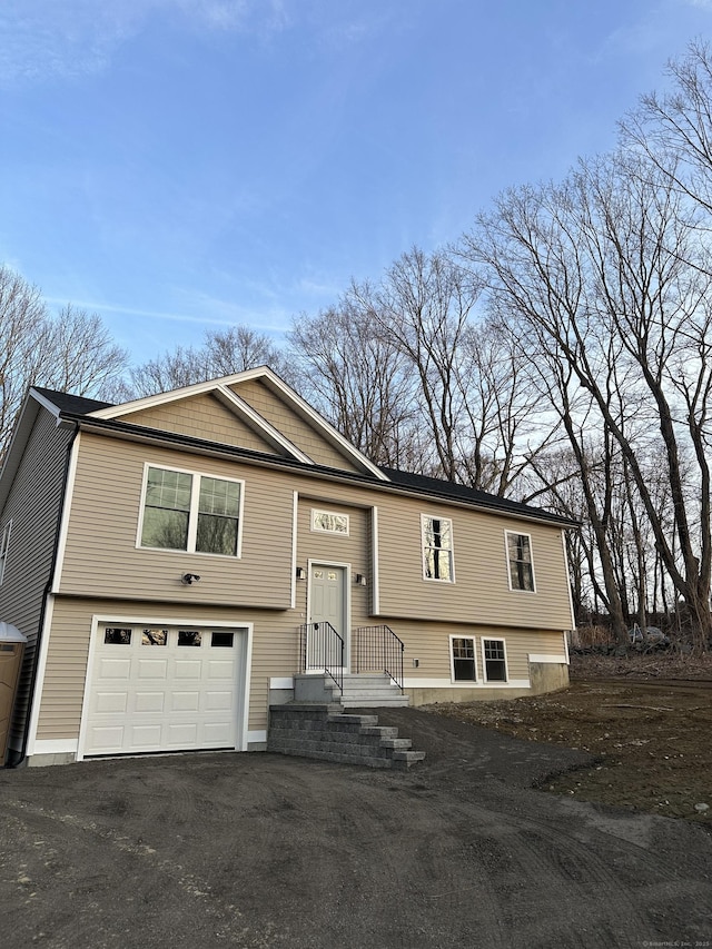 raised ranch featuring a garage and aphalt driveway